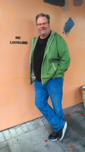 Kelly Loitering - LifeRing Secular Recovery Photo of convenor Kelly leaning against a wall that says "No loitering".