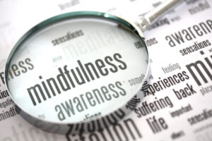 magnifying glass highlighting the word midfulness amid other mental health related words.